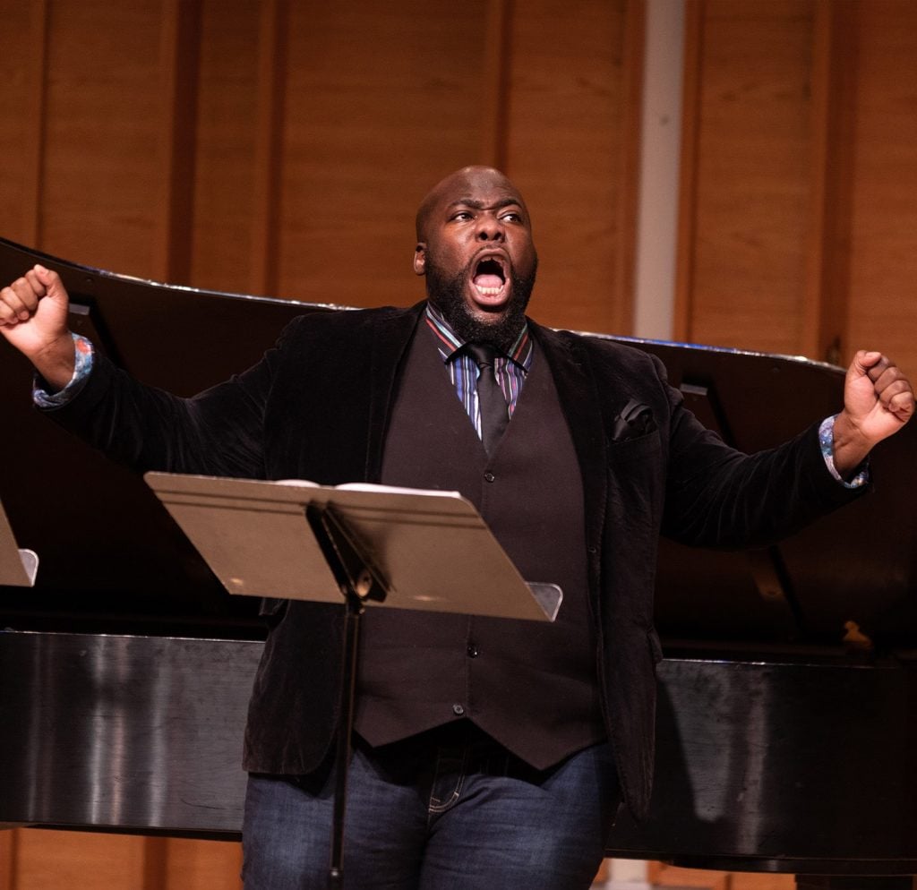 Errin Brooks holds his hands out while singing